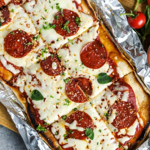 grilled pizza in tin foil with parsley and pepperoni on top