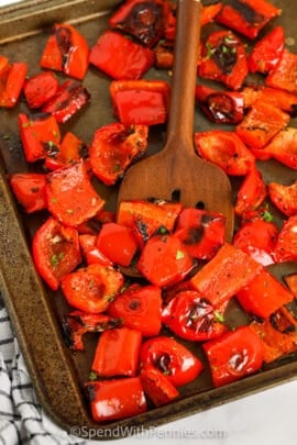 Roasted Red Peppers cooked on a baking sheet with a spoon
