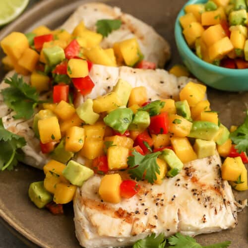 Grilled Mahi Mahi topped with mango salsa on a brown plate