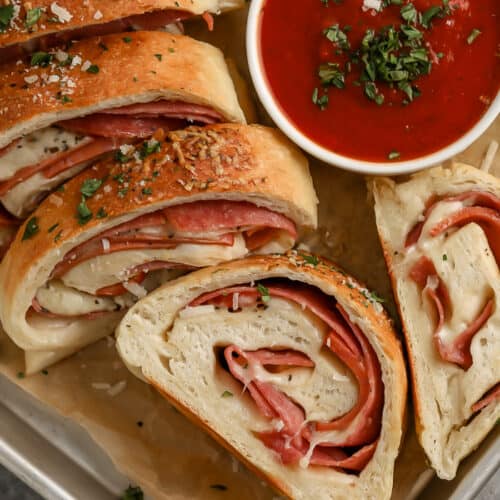 sliced pepperoni roll on a pan with red sauce