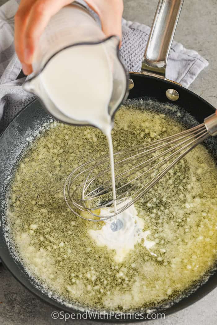 adding cream to butter and garlic in a skillet