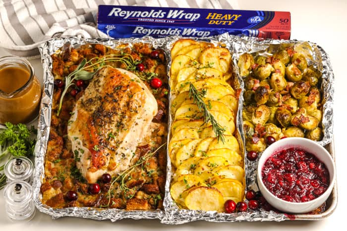 turkey dinner on a sheet pan with a bowl of cranberry sauce