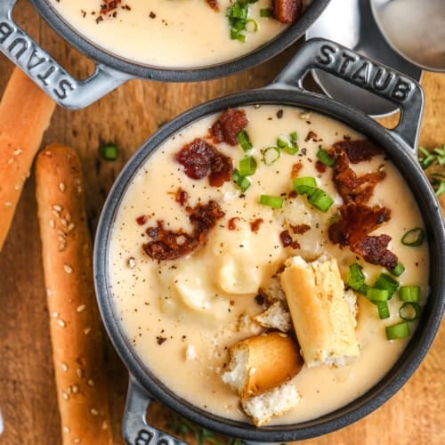 two bowls of cheesy potato soup garnished with green onion and bacon