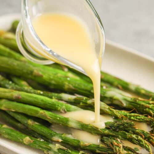 pouring beurre blanc over asparagus to show How to Make Beurre Blanc