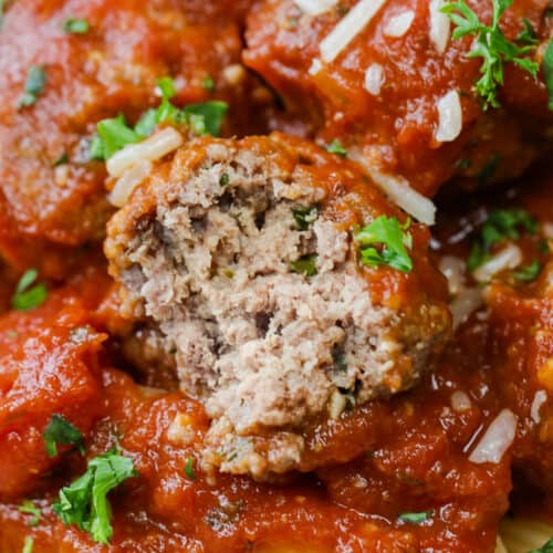 close photo of the inside of a crockpot meatball with tomato sauce