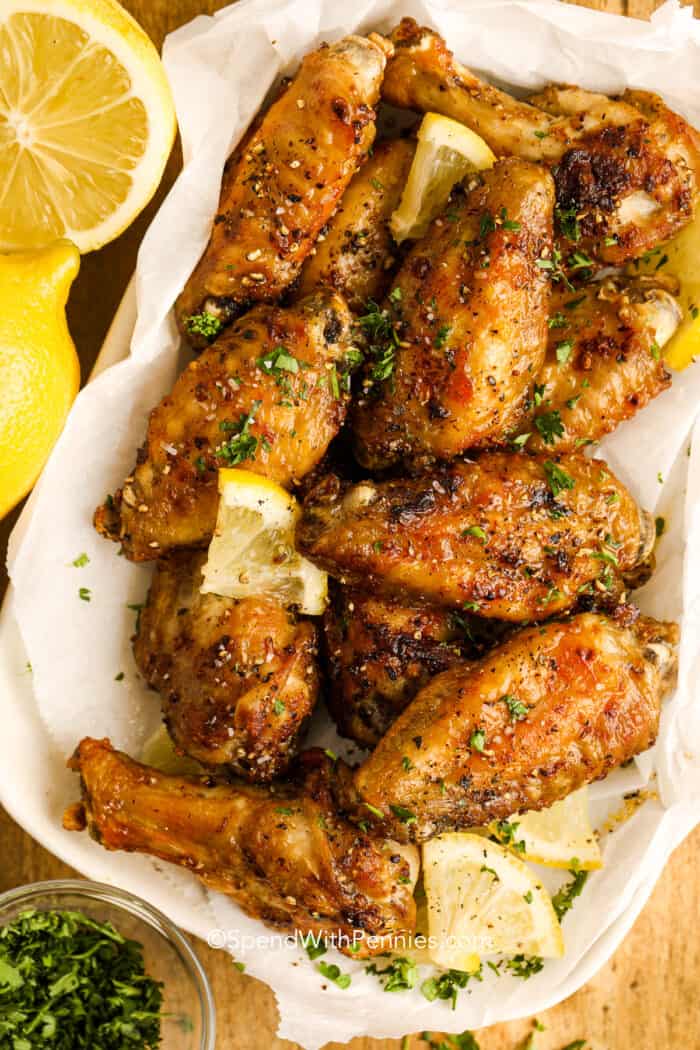 lemon pepper wings on a plate with small lemon wedges
