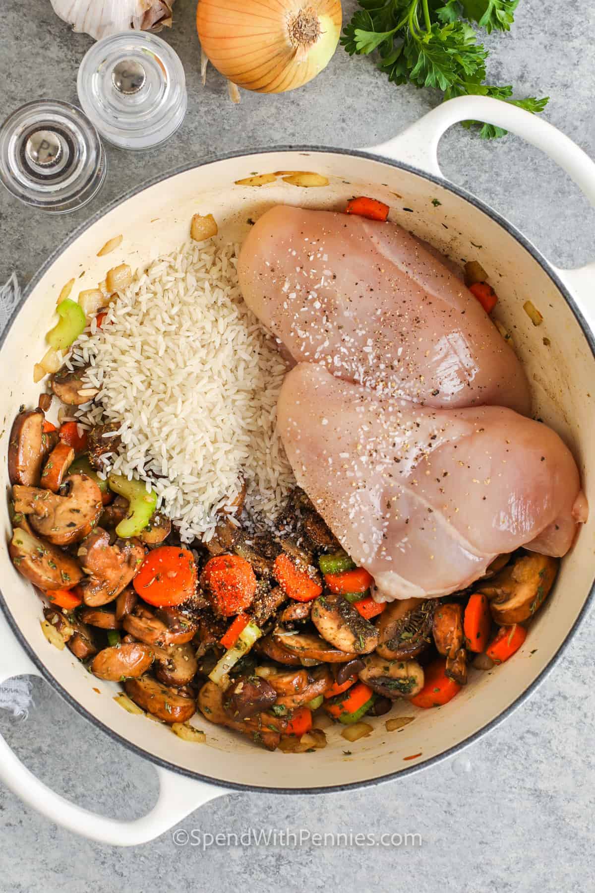 This chicken and mushroom soup is hearty, brothy, and full of comforting flavor from chicken broth, thyme, poultry seasoning, vegetables, and long grain rice. It cooks in one pot, which means fewer dishes and a simple cleanup after dinner. Brown mushrooms add deeper flavor, while white mushrooms keep it mild and classic. Serve this family-friendly soup for leftovers and easy lunches. #spendwithpennies adding chicken and rice to pot to make Chicken Mushroom Soup