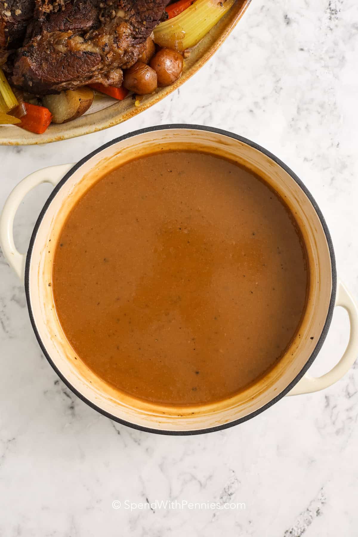 This pot roast recipe is the ultimate comfort food, slow-cooked until tender with carrots, potatoes, and celery. A rich broth of red wine, garlic, and herbs infuses every bite with savory flavor. Searing the beef first locks in juices and creates a golden crust. Whether you serve it with pan juices or gravy, this dish is perfect for cozy nights or Sunday dinners. #spendwithpennies pot roast gravy in a Dutch oven