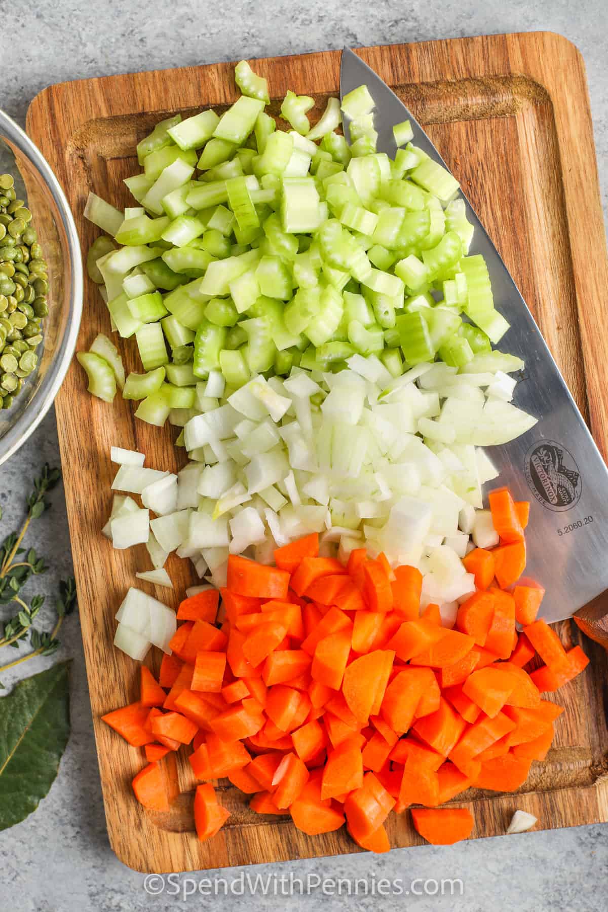 Chopped onions, carrots, and celery on a cutting board.