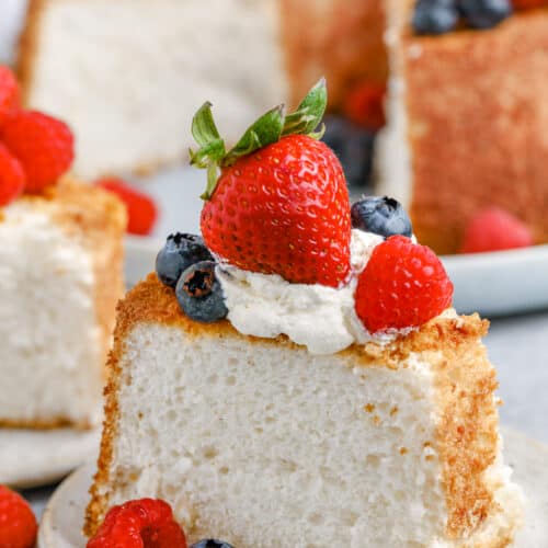 slice of Angel Food Cake on a plate with fresh fruit and whipped cream