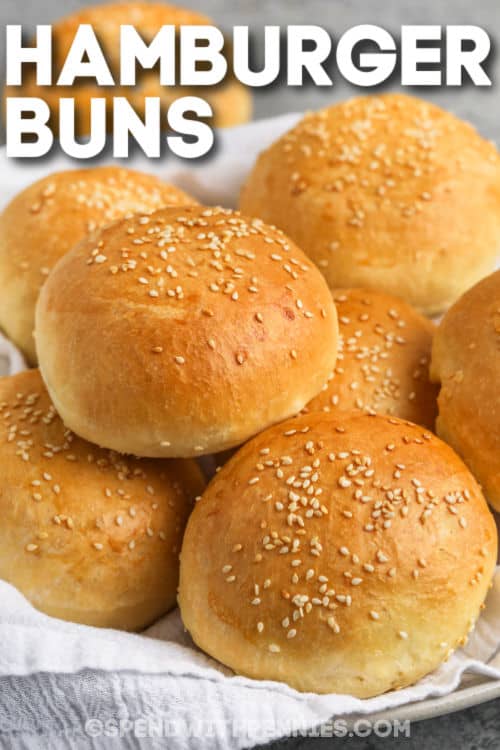 The perfect pub-style hamburger buns can be made at home with this easy recipe. Warm and soft hamburger buns straight from the oven are the best with juicy burgers from the grill, as breakfast sandwiches, or made into garlic bread! These buns are not like store-bought hamburger buns. Similar to brioche bread, they are fluffy and oh-so-good! #hamburgerbuns #homemadehamburgerbuns #briochehamburgerbuns #spendwithpennies plated Hamburger Buns with a title