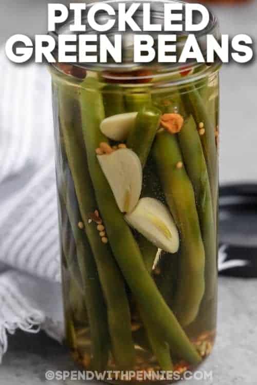 Make these tasty and crunchy pickled green beans and store them in the refrigerator for a quick and tasty snack or salad topper. Make them spicy, hot, or sweet with different add-ins, or stick to the recipe for a garlic-flavored pickled treat! #pickledgreenbeans #spendwithpennies #nocanning #howto jar of Quick Pickled Green beans with writing