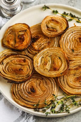 Roasted Onions on a serving plate with thyme as garnish