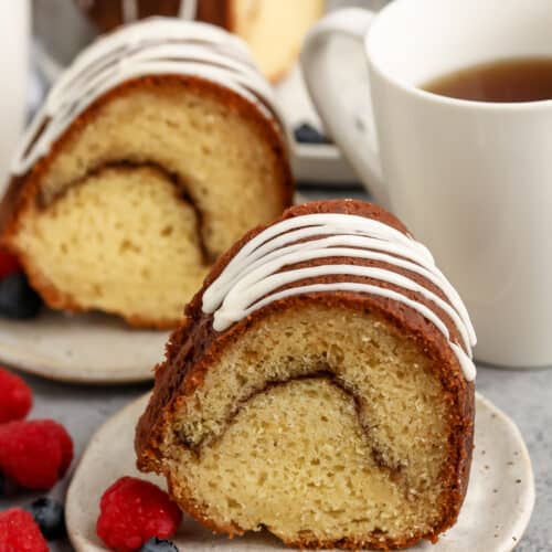 slice of Sour Cream Coffee Cake on plates with a coffee beside it