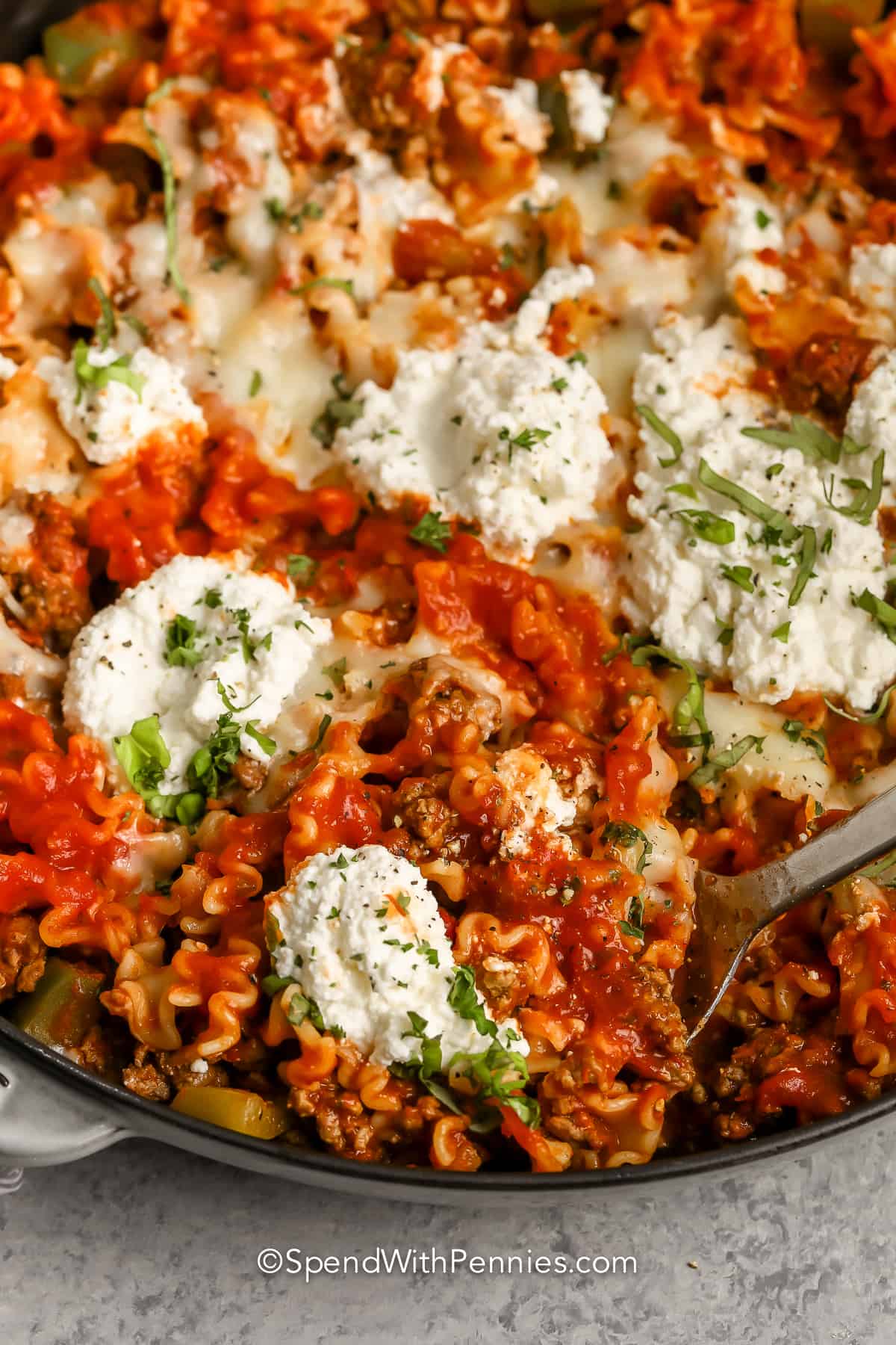 taking a spoonful out of a pan full of Cheesy Lasagna Skillet
