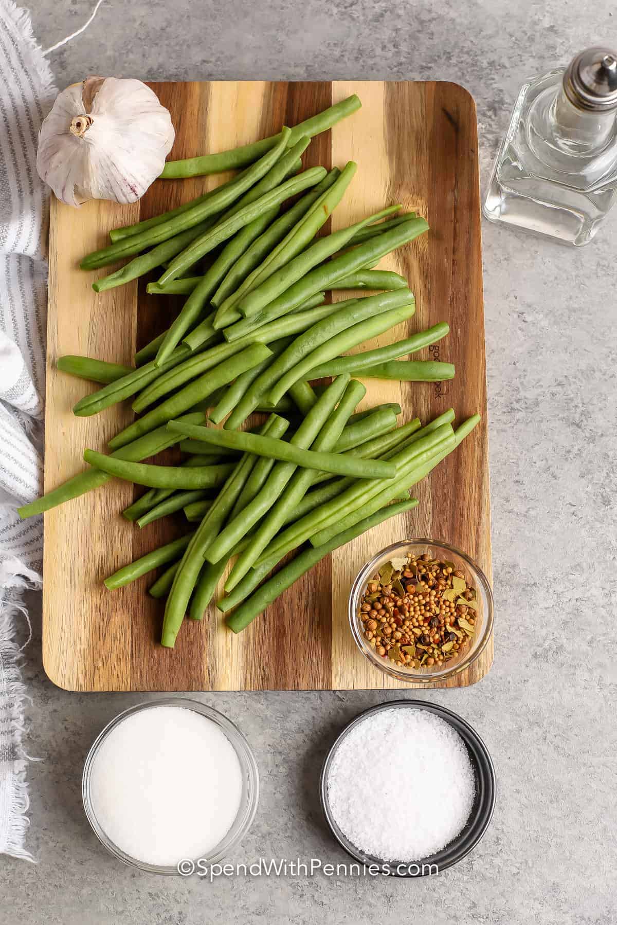 Make these pickled green beans to add to an antipasto platter! They don't take long to make and have simple ingredients. These quick and easy pickled beans don't need pressure canning, they can just be stored in the refrigerator. You can even enjoy them with cocktails or in a salad! #pickledgreenbeans #spendwithpennies #nocanning #howto beans and ingredients in bowls to make Quick Pickled Beans