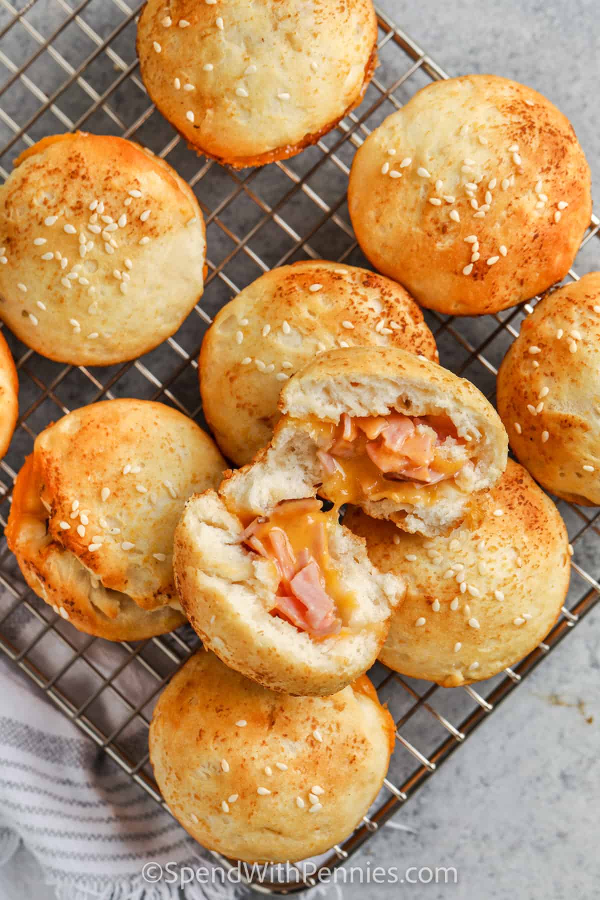 Make these savory ham and cheese stuffed biscuits for breakfast or lunch. Pillsbury dough biscuits are the secret ingredient that makes this recipe so easy to make. Simply cut them open, add the ham and cheese and cook in the oven. #hamandcheesestuffedbiscuits #stuffedbiscuits #biscuits #spendwithpennies Stuffed Biscuits on a cooling rack