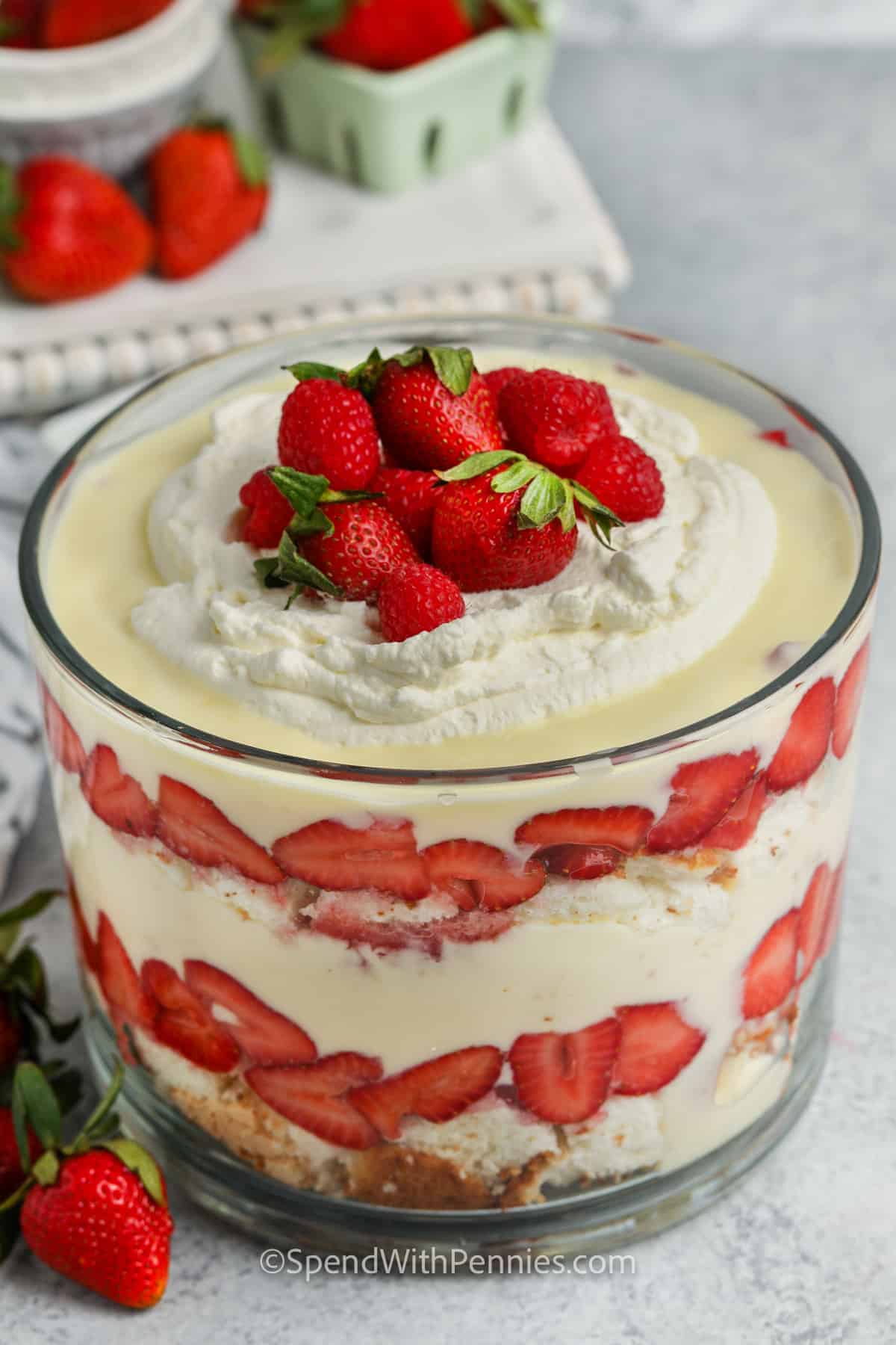 A layered trifle is so easy to make. Guests will gush over the impressive presentation of this fresh & fruity dessert. Sweet white cake, custard or vanilla pudding, and strawberries topped off with whipped cream. It's a summer favorite! #trifle #triflerecipe #easytrifle #spendwithpennies finished Trifle with strawberries and whipped cream on top