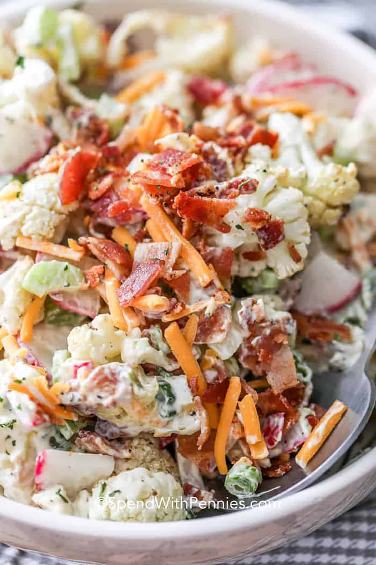 Make this loaded cauliflower salad as a keto side dish. Crispy cauliflower, spicy radishes, and celery are tossed with bacon and a creamy dressing for the best summer salad. No cauliflower? No problem. Simply replace it with broccoli. #loadedcauliflowersalad #cauliflowersalad #cauliflowersaladrecipe #spendwithpennies close up of Cauliflower Salad
