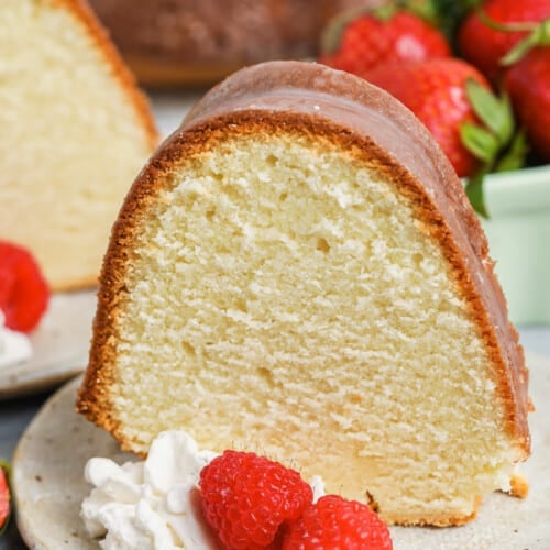 Cream Cheese Pound Cake on a plate with raspberries and whipped cream