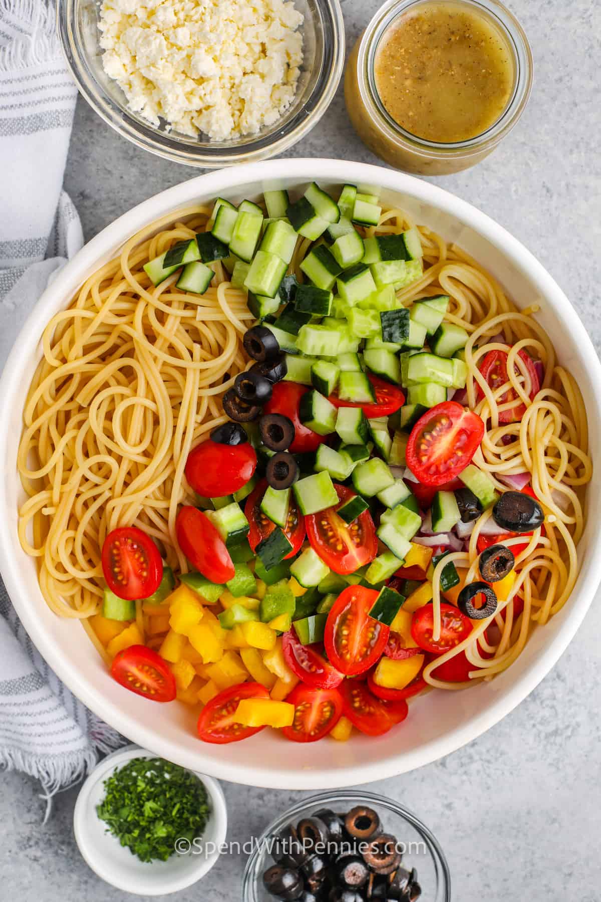 adding vegetables to pasta to make Favorite Spaghetti Salad