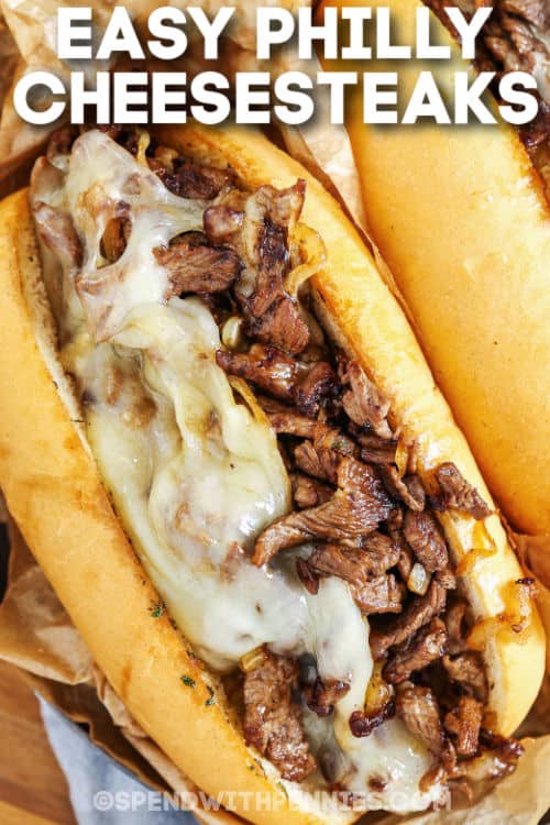 Philly Cheesesteaks are one of the best sandwiches out there! Seasoned steak, grilled with onion, melted provolone, and served on a hoagie. Tailgate parties, backyard BBQs, or just dinner at home with the family, these are perfect for any occasion! #spendwithpennies #phillycheesesteaks #lunch #recipe #phillycheesesteak plated Philly Cheesesteaks subs with writing