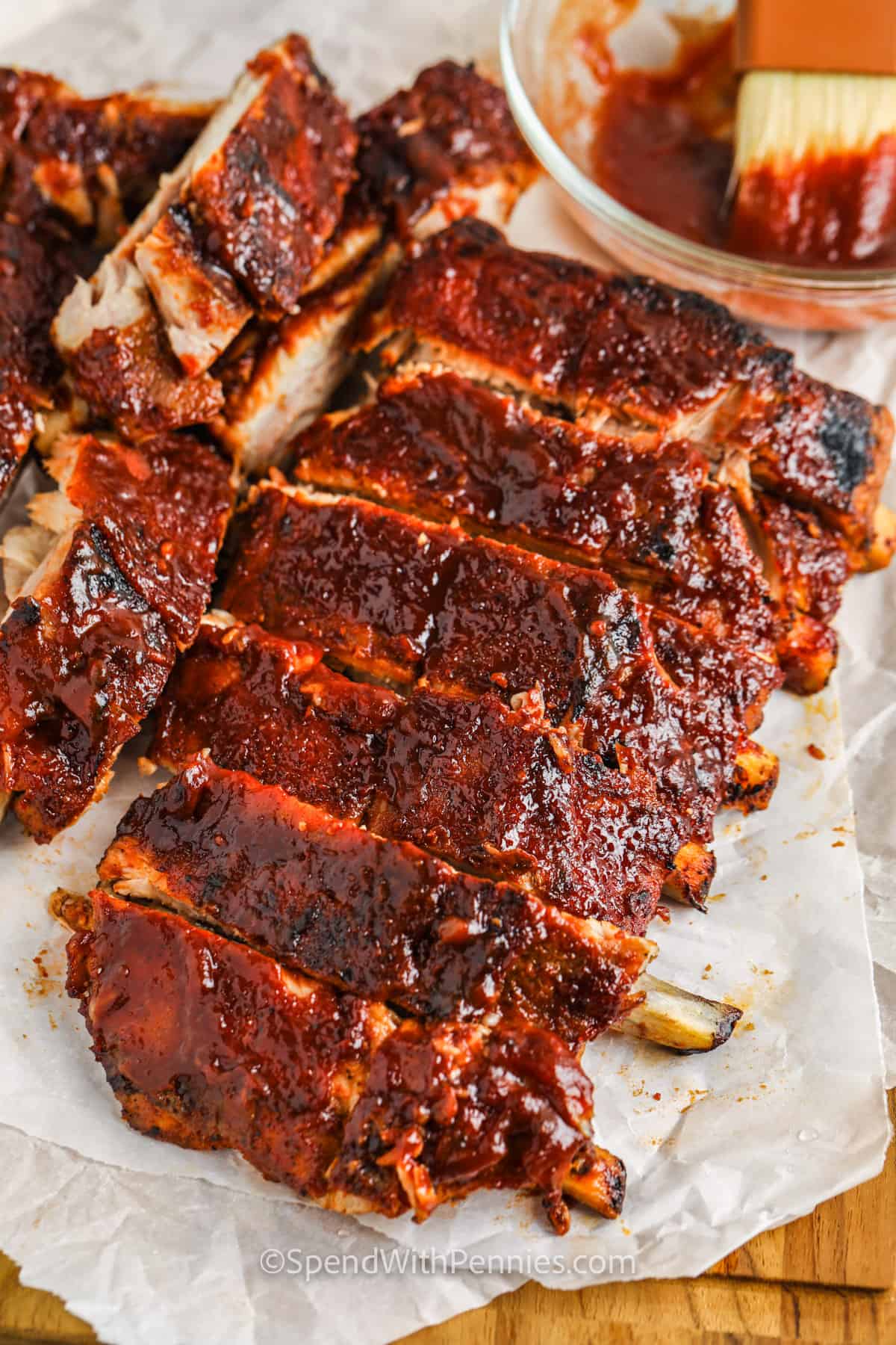 Oven-baked ribs come out melt-in-your-mouth tender and so flavorful. Seasoned and cooked low and slow, these tender ribs are sealed off with a flash grill and some BBQ sauce! Serve with a side of beans or fresh salad for the perfect meal any time of the year. #ovenbakedribs #ribs #recipe #spendwithpennies sliced Oven Baked Ribs