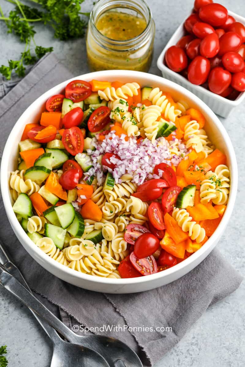A simple and easy-to-make Italian pasta salad recipe is just what summer needs. Top this creamy salad with some ham and mozzarella cheese for a finishing touch. #spendwithpennies #pastasaladrecipe #recipe #pastasalad Ingredients for an easy pasta salad in a white serving bowl