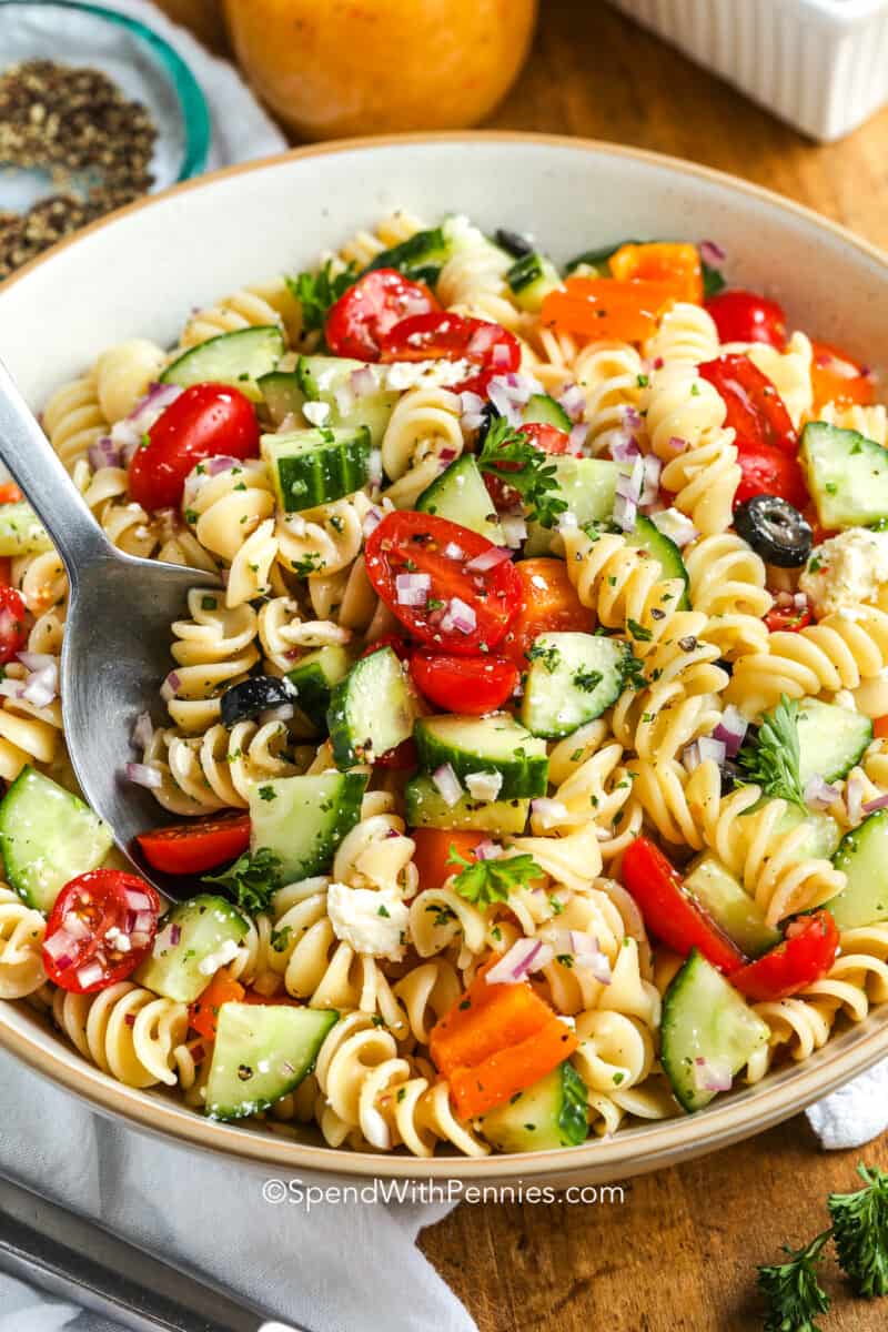 close up of an easy pasta salad in a white serving bowl with a serving spoon