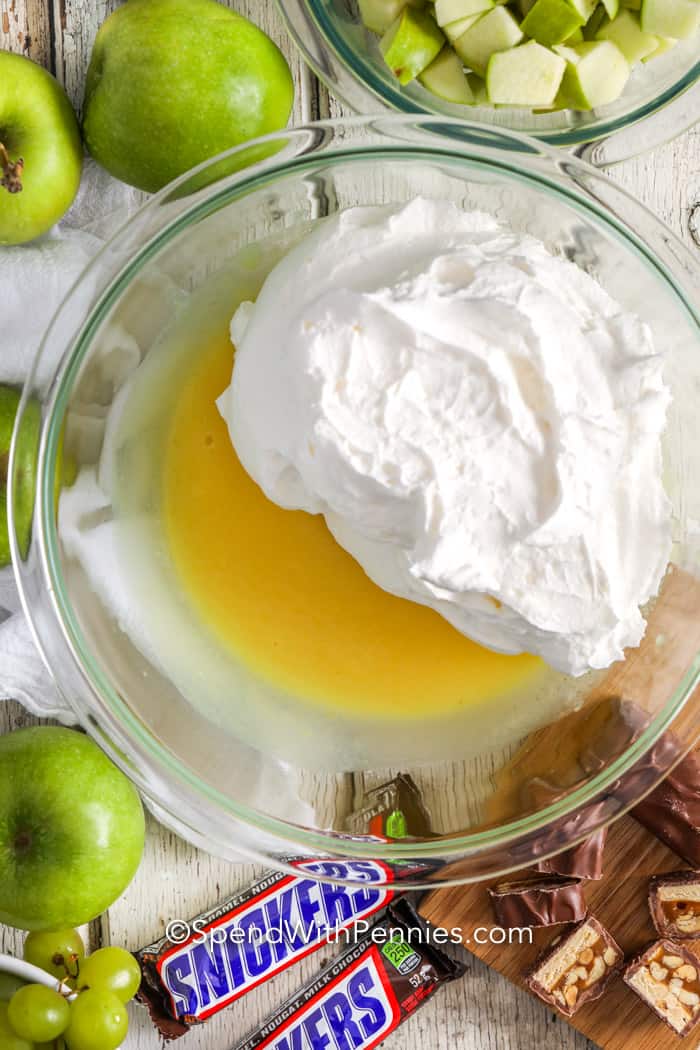 Snicker Salad is an easy dessert made with apples, grapes, Snickers & pudding. Great for potlucks, parties, or a family treat! This simple 6 ingredients dessert is perfect to make ahead, just combine the ingredients and chill before serving. #spendwithpennies #snickersalad #dessert #snickerapplesalad #easy #foracrowd butterscotch pudding and whipped topping in a bowl