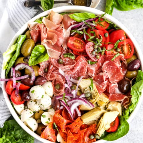 antipasto salad in a while bowl with dressing on the side