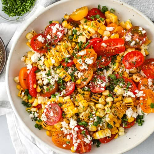 grilled corn and tomato salad topped with feta cheese and parsley
