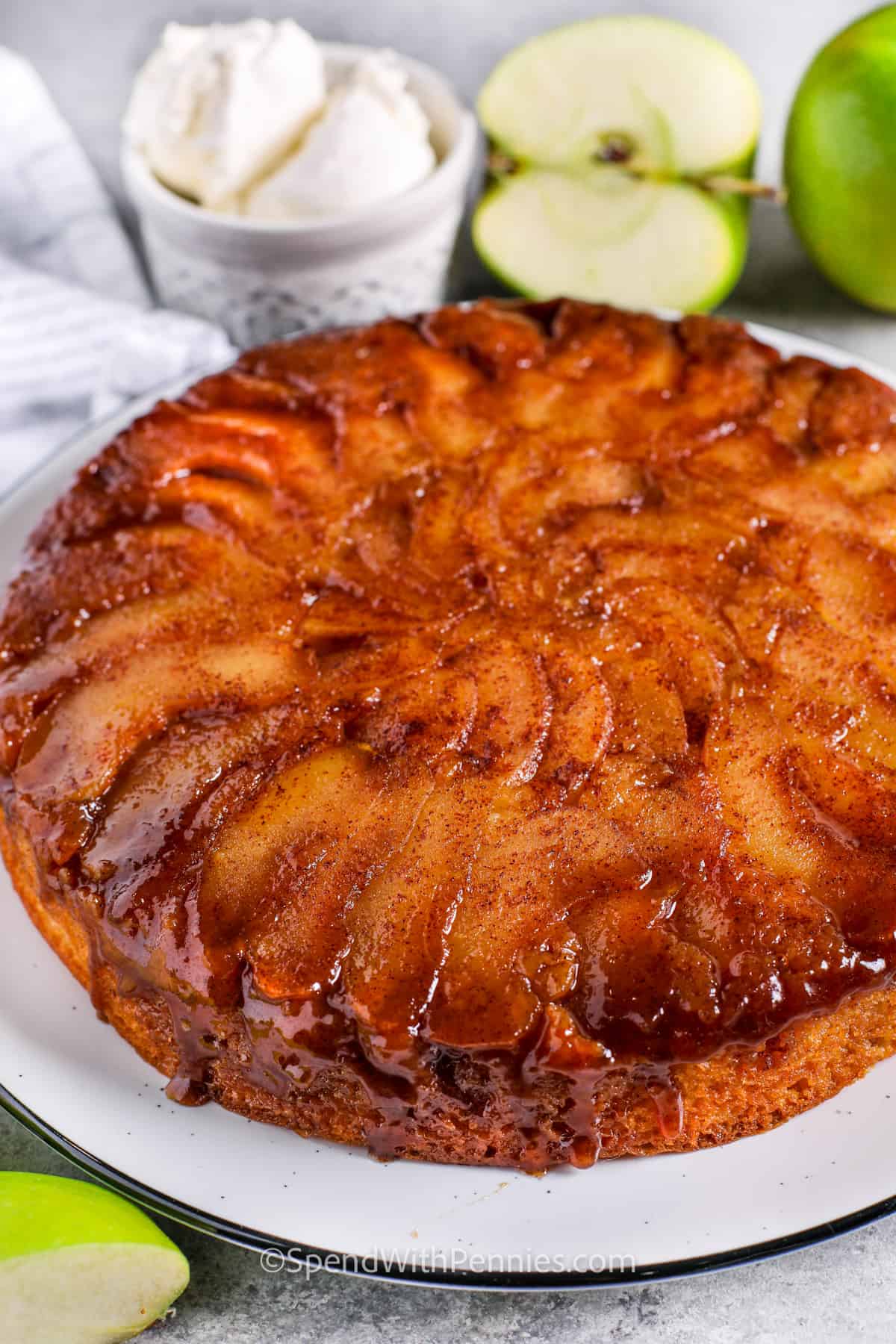 This recipe for apple cake is made in the style of an upside-down cake! Slices of cinnamon spiced apple are placed in the bottom of a pan with butter and brown sugar, then topped with a homemade yellow cake batter and baked until golden brown. Flip the pan and slip it off to reveal a layer of juicy, sticky, caramelized apples on top. The perfect dessert for apple-picking season! #applecakerecipeeasy #applecake #spendwithpennies #applecakerecipe #moistapplecakerecipes Brown Sugar Apple Cake on a plate