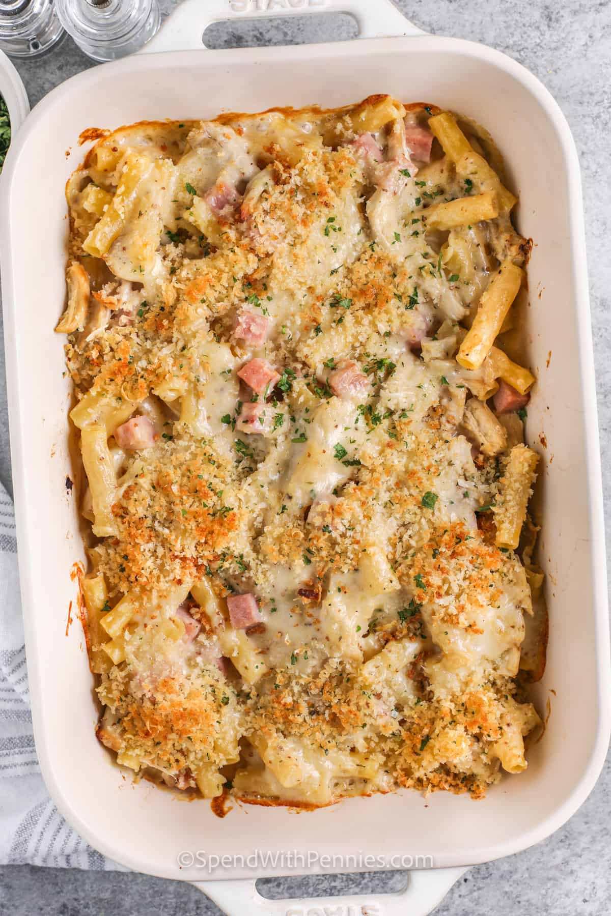 No need to make stuffed chicken, this easy chicken cordon blue casserole is simple to make and tastes just as delish! It's made with pasta in a cheesy cream sauce, and it's simple to make it into a keto or low carb recipe if desired, just leave out the pasta and Panko breadcrumbs, and sub cauliflower rice. #chickencordonbluecasserole #easyrecipe #withpasta #spendwithpennies Chicken Cordon Bleu Casserole cooked in a dish