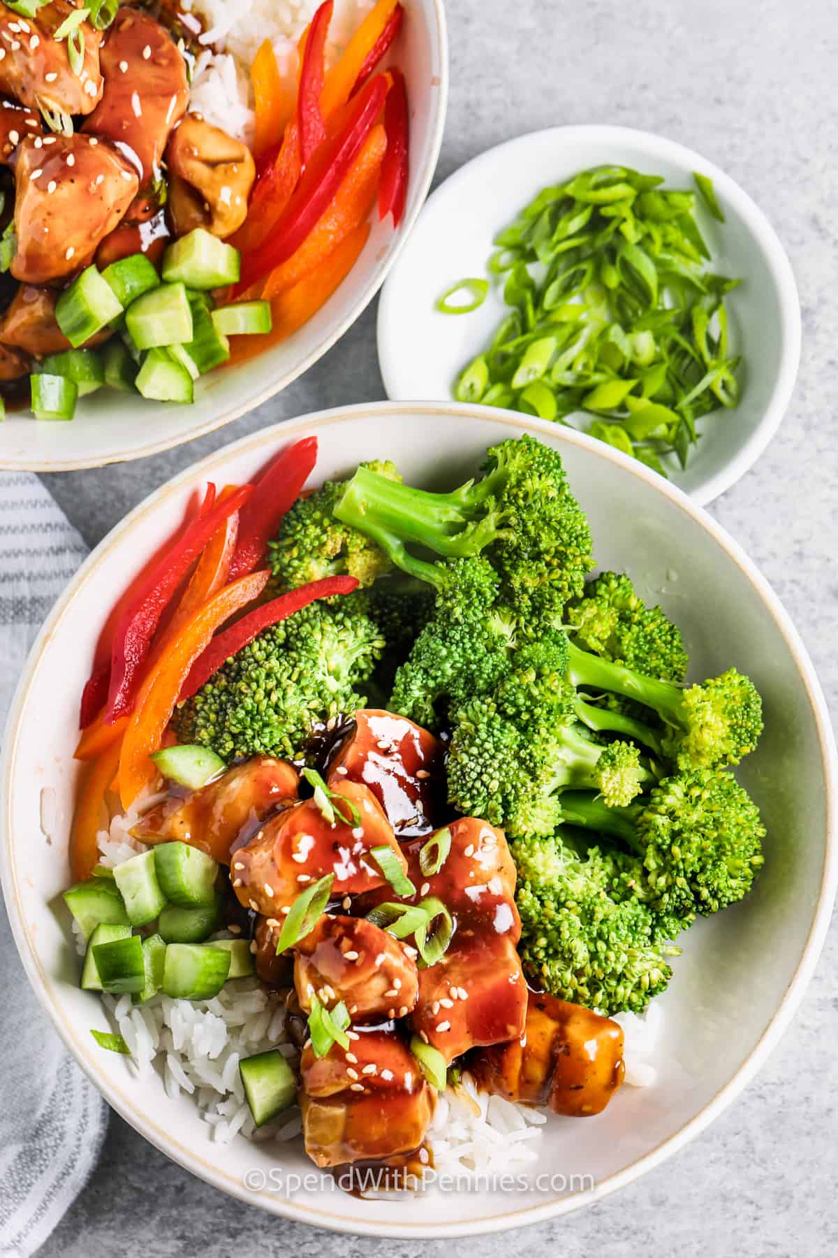 Here's the best teriyaki chicken bowl recipe ever, that you can make in just 30 minutes or less! Chunks of juicy and tender chicken are stir fried in a savory homemade teriyaki sauce, with tender-crisp broccoli and served over fluffy cooked rice. It can be changed to accommodate any of your favorite vegetables, mushrooms, or even pineapple. Tastes great with a sprinkle of toasted sesame seeds. #spendwithpennies Teriyaki Chicken Bowls with rice and onions