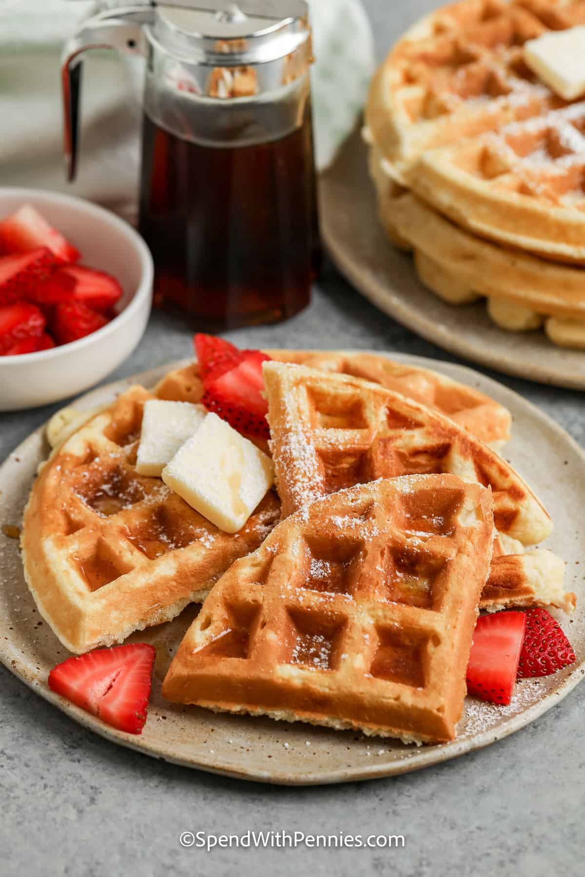 This Belgian waffle recipe is easy enough for every day but is always a welcome treat for Sunday brunch or even as a dessert! Buttermilk and whipped egg whites make these waffles extra light and crispy, while egg yolks, melted butter, and a touch of sugar and vanilla give them a fragrant fluffy richness. Drenched in syrup or your favorite sweet toppings, waffles will brighten any morning! #easybelgianwafflerecipe #spendwithpennies #belgianwafflerecipe #bestbelgianwaffles belgian waffles on a plate