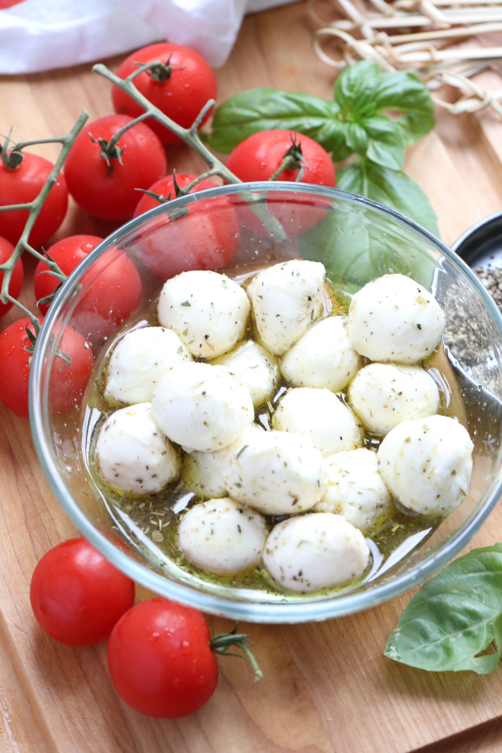 This Caprese skewer recipe is perfect for parties. It’s a popular combination of cherry tomatoes, olive oil marinated mozzarella balls, and fresh basil. These easy skewers are a quick, healthy, low carb appetizer that everyone loves! #spendwithpennies #capreseskewers #caprese #appetizer marinated cheese with tomatoes beside it to make Caprese Skewers