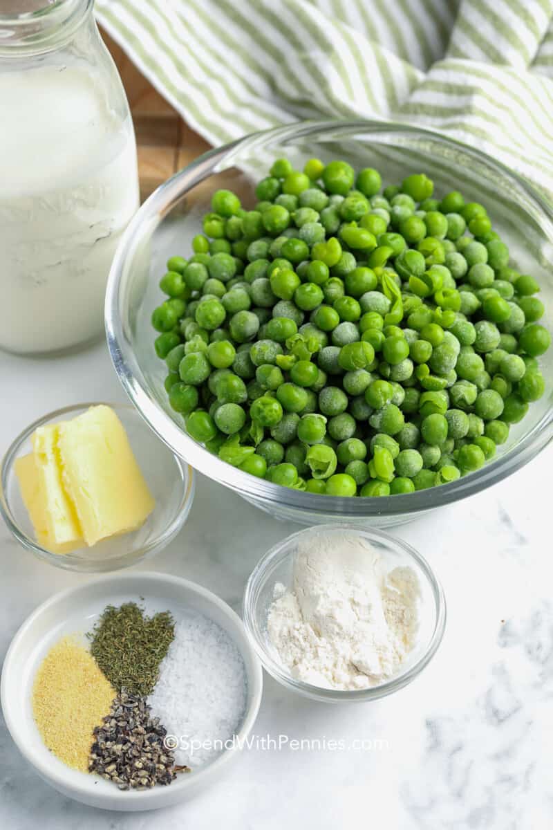 Färska, frysta eller konserverade krämade ärtor gör en högtidsmiddag festlig. Krämig, fräsch och färgstark, detta enkla recept är en vinnare. #spendwithpennies #creamed peas #sidedish #recept ingredienser för gräddade ärtor på en bänk med en kökshandduk