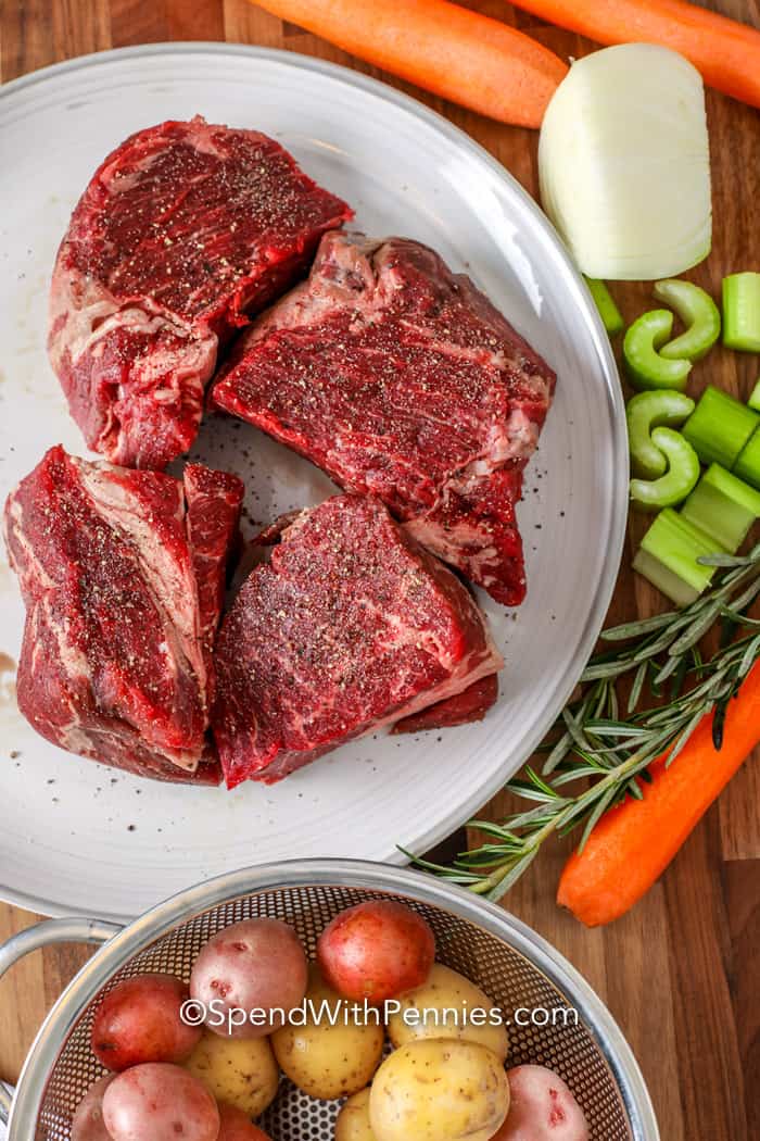 Once you make this Instant Pot pot roast recipe your family will beg for it again! It takes only an hour to make, but has a slow cooked flavor! Chuck roast or another cut of beef is pressure cooked until fork tender with carrots, creamy baby potatoes, and seasonings to make the most delicious savory dinner ever! A rich gravy seasoned with red wine, garlic, and rosemary is the crowning touch. #instantpotpotroast #spendwithpennies #ultimateinstantpotpotroast #instantpotpotroastwithvegetables ingredients for instant pot pot roast on a wood board