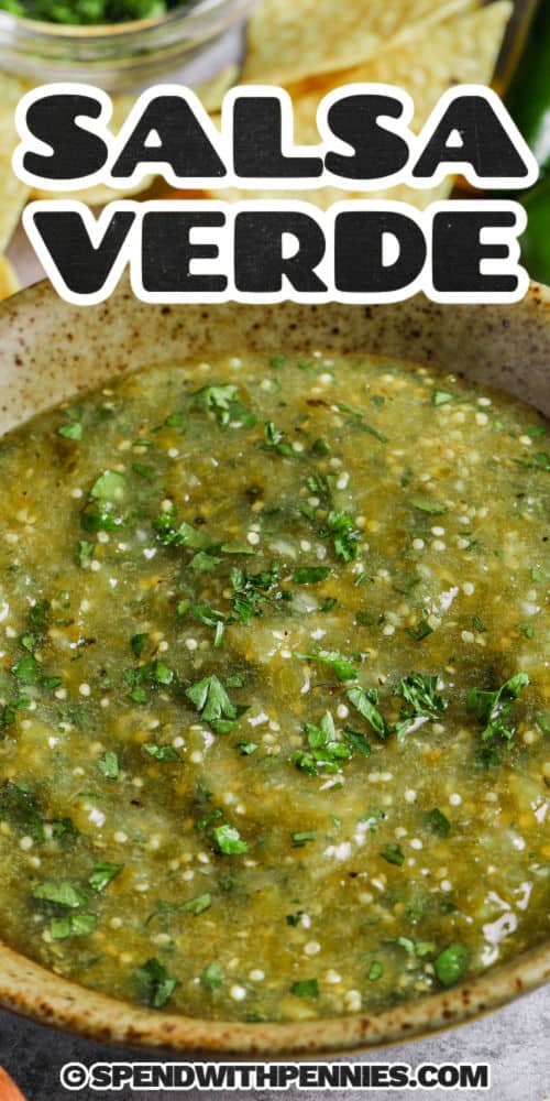 This green salsa verde recipe is packed with bright and zesty flavors and all fresh ingredients! Tomatillos and serrano or jalapeno peppers or other green peppers are roasted under an oven broiler, then peeled and popped into the food processor with onion, garlic, and cilantro. The result is a healthy condiment for tacos, enchiladas or chili con carne! Why buy salsa verde, when you can make it in minutes with no preservatives? #salsaverde #spendwithpennies #salsaverderecipe #mexicansalsaverde bowl of Salsa Verde with a title