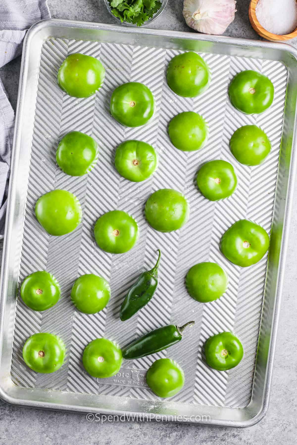 tomatillos on a sheet pan before baking to make Salsa Verde