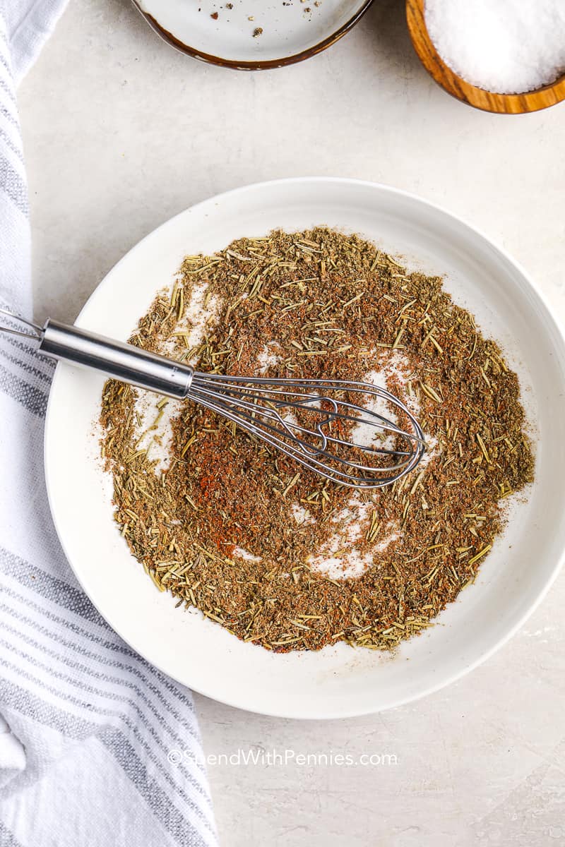 Turkey seasoning is a great way to add some extra flavor to your bird this holiday. We also sprinkle it on potatoes, casseroles, and veggies for an extra boost of flavor! It’s so easy to make with simple ingredients, and keeps in the pantry for up to 6 months. #turkeyseasoning #homemade #seasoning #spendwithpennies a whisk stirring homemade turkey seasoning on a plate
