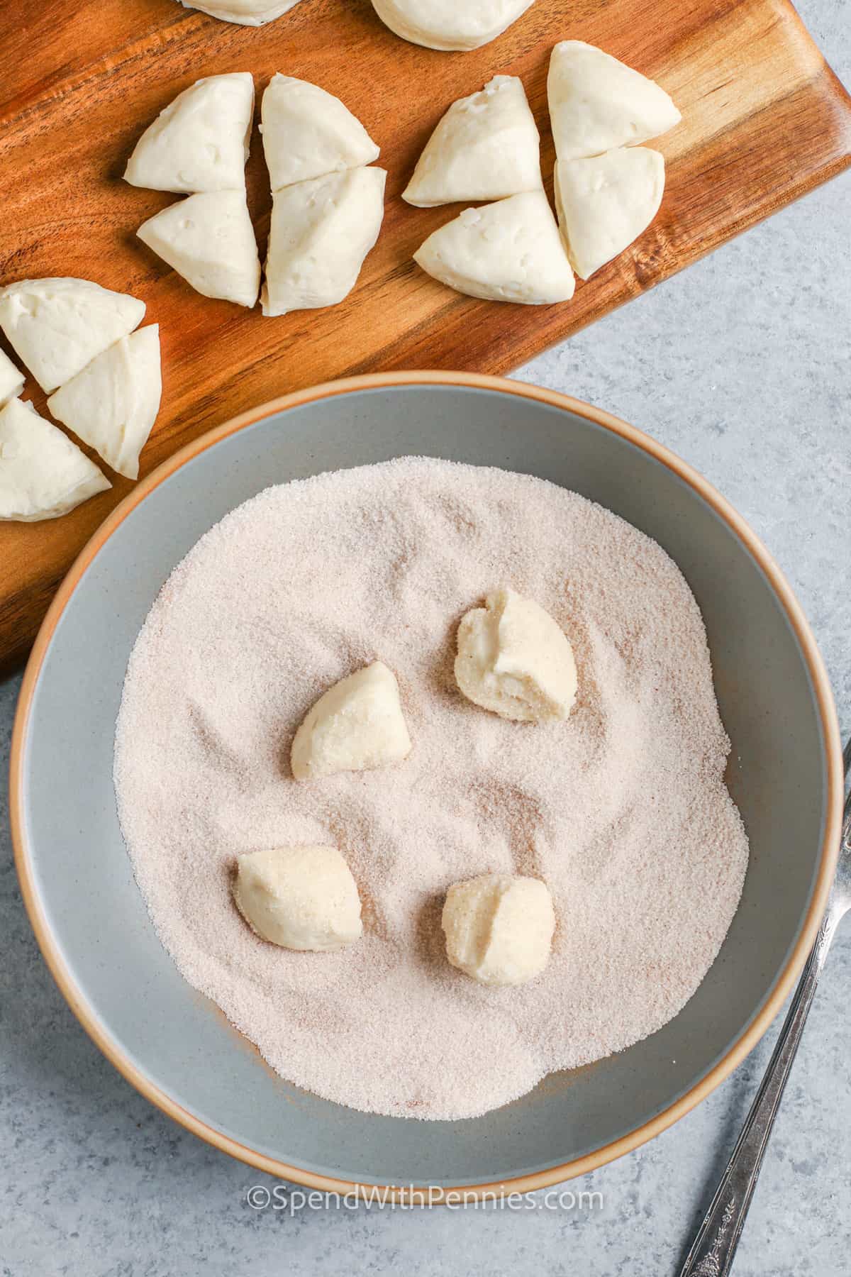 dipping bread pieces in sugar and cinnamon to make Monkey Bread