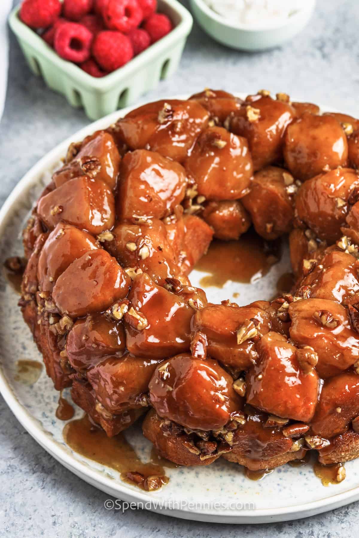 This delicious recipe for monkey bread with pecans is a sweet addition to any special breakfast. Pillsbury biscuit dough from a can is rolled into balls, coated with butter, and tossed with cinnamon sugar. Then the balls are layered in a Bundt pan with chopped pecans and baked until golden brown and glazed. #monkeybread #spendwithpennies #monkeybreadrecipe #monkeybreadwithcannedbiscuits plated Monkey Bread