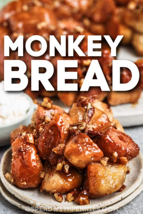 Buttery monkey bread with cinnamon and pecans is so much fun to pull apart and eat for breakfast or snacks. Pillsbury biscuit dough from a can is rolled into balls, coated with butter, and tossed with cinnamon sugar. The balls are layered in a Bundt pan with chopped pecans, or apples and raisins, and baked until golden brown and glazed. Try a pizza version with parmesan, garlic powder, and Italian seasonings! #monkeybread #spendwithpennies #monkeybreadrecipe #monkeybreadwithcannedbiscuits plated Monkey Bread with a title