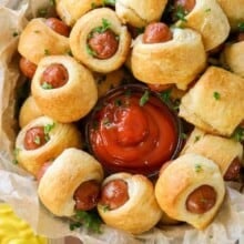 cooked Pigs in a Blanket on a plate with ketchup and mustard dips