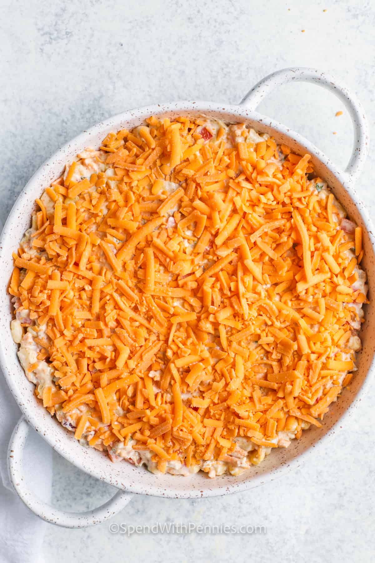 adding cheese to dish to make Creamy Baked Corn Dip