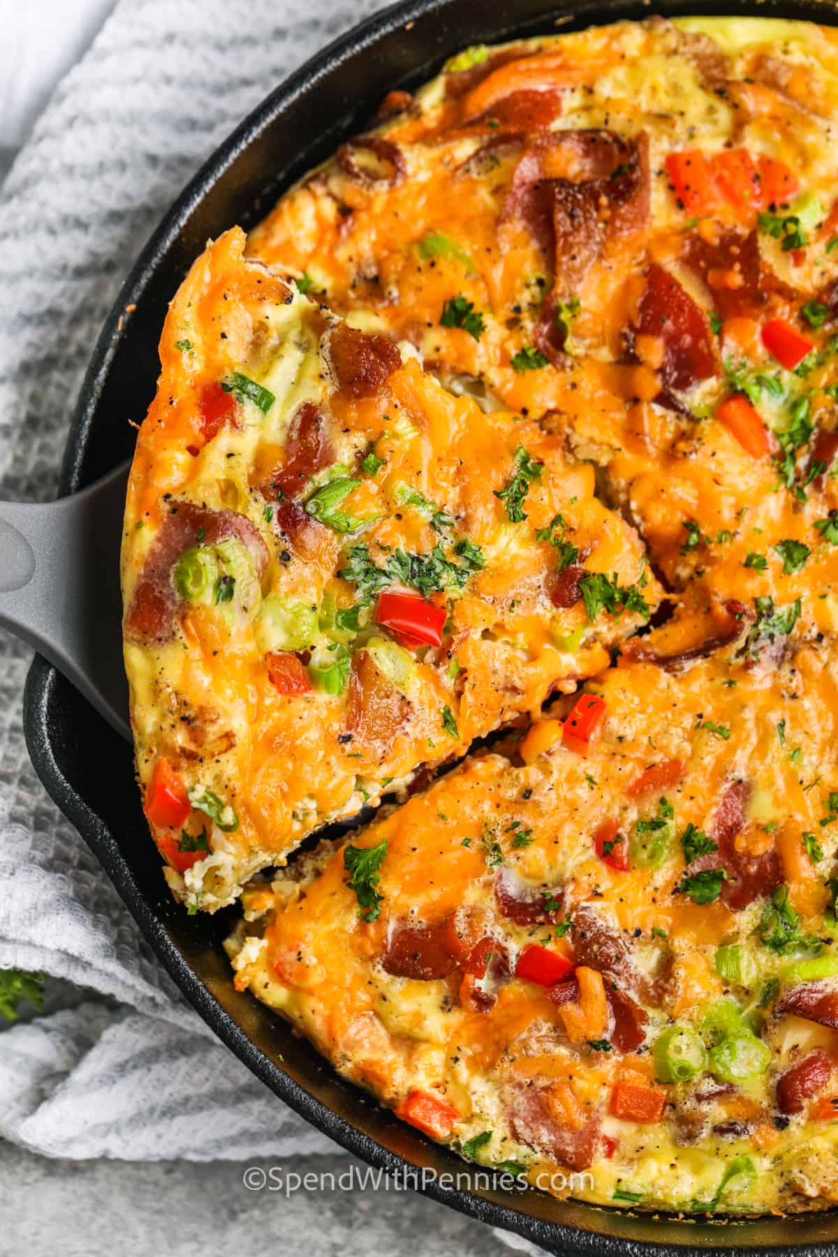 This tasty frittata recipe is a great way to use up leftovers! Make it as cheesy or meaty as you like, or go for a vegetable version. Swap out potatoes for hashbrowns, leftover roasted or boiled potatoes, or home fries. Even leftover pasta can be chopped up and added in place of potatoes. For a low-carb version, substitute some roasted cauliflower or cauliflower rice. #frittata #frittatarecipe #breakfast #spendwithpennies taking a slice of frittata out of the pan to show How to Make a Frittata