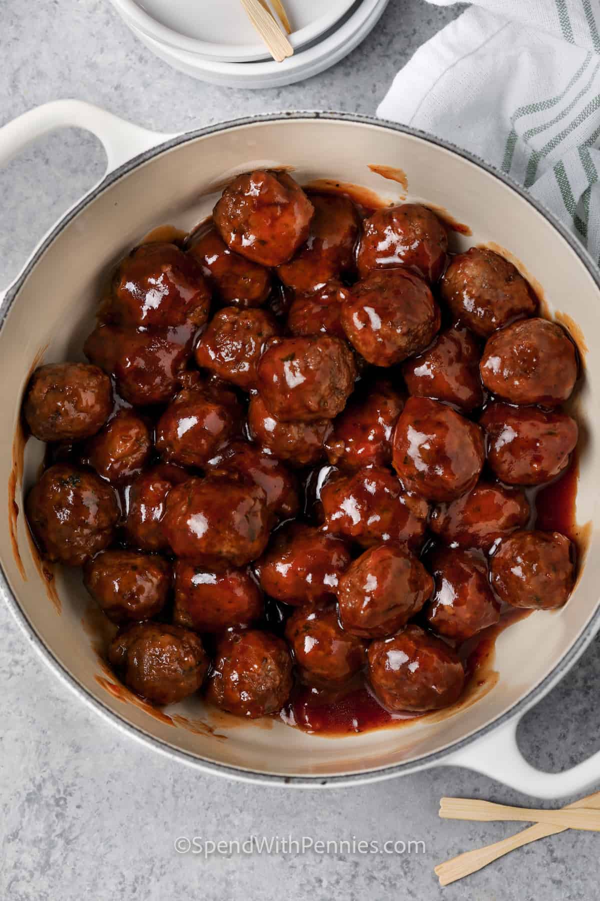 Everybody loves cocktail meatballs and this recipe makes them perfectly savory, sweet, and sour. Just place precooked frozen meatballs in a saucepan with apricot preserves and barbecue sauce and heat until melted and bubbling hot. Keep them warm in a Crock Pot for self-service. They’re also delicious made with grape or cranberry jelly. #cocktailmeatballs #spendwithpennies #bestcocktailmeatballsrecipe #sweetandsourmeatballswithjelly mixing meatballs with sauce to make Sweet and Sour Meatballs
