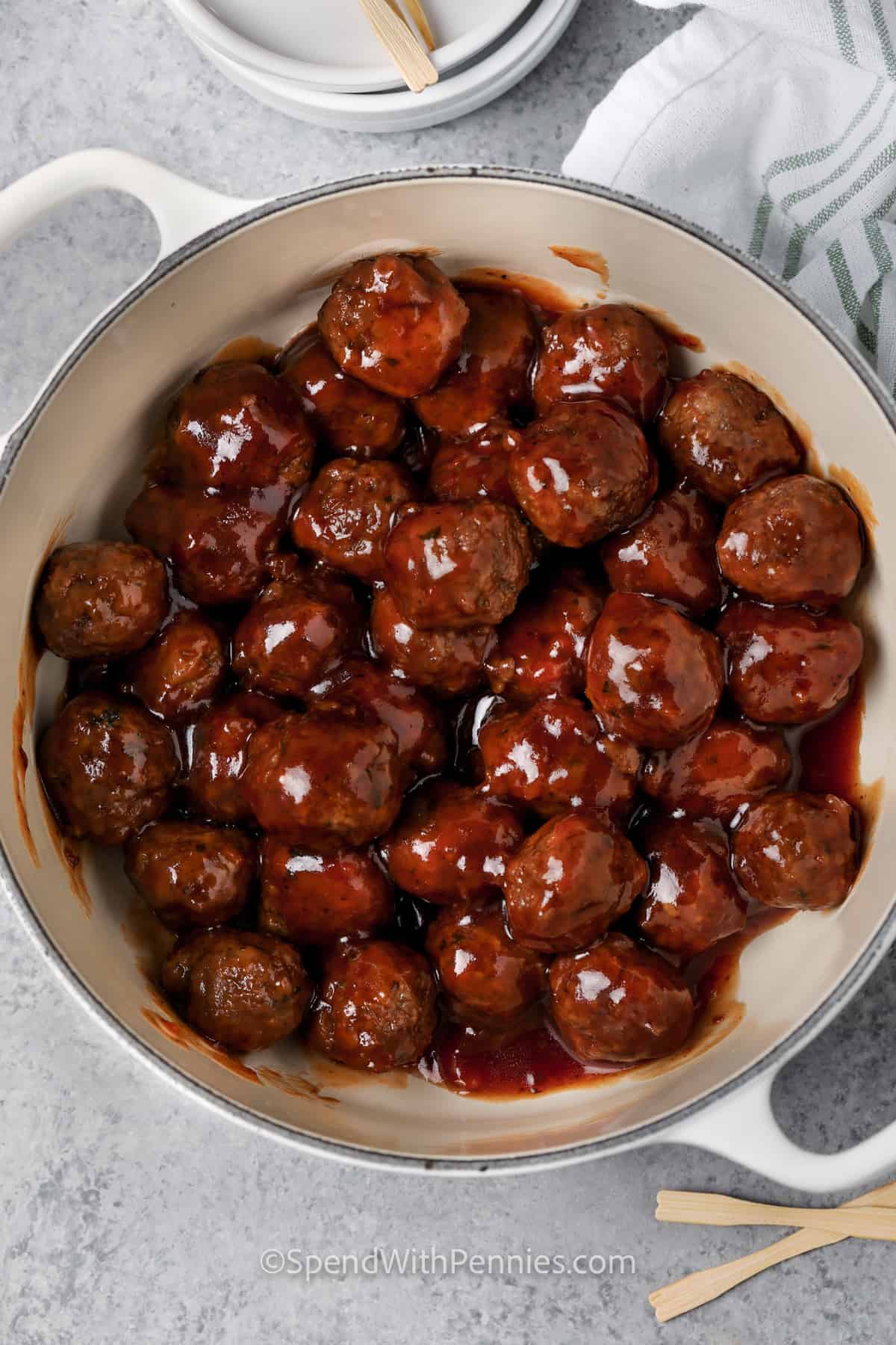 mixing meatballs with sauce to make Sweet and Sour Meatballs